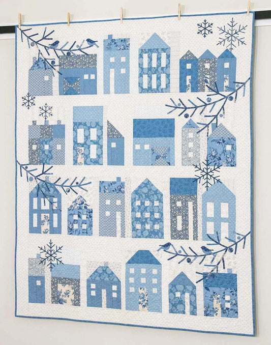 Edyta Sitar Quilt with blue house pattern and snowflakes on a white background