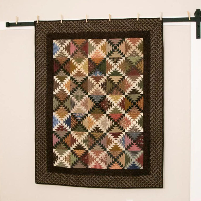 Quilt hanging on a wall with a wooden floor and white wall in the background