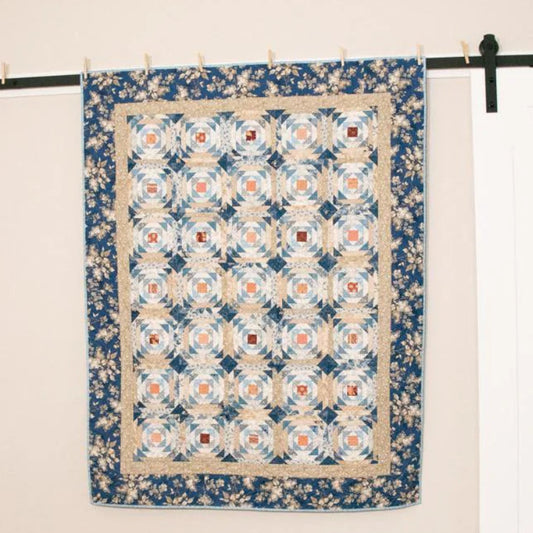 Quilt hanging on a wall with 'Laundry Basket Quilts' branding.
