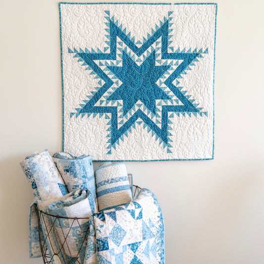 Blue and white quilt with geometric pattern on a wall