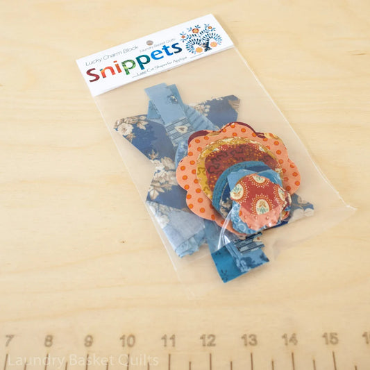 Snippets - Lucky Charm Block by Laundry Basket Quilts — laser cut hand and machine appliqué fabric shapes in blue florals and orange polka dot prints, packaged in a clear bag with Snippets header card