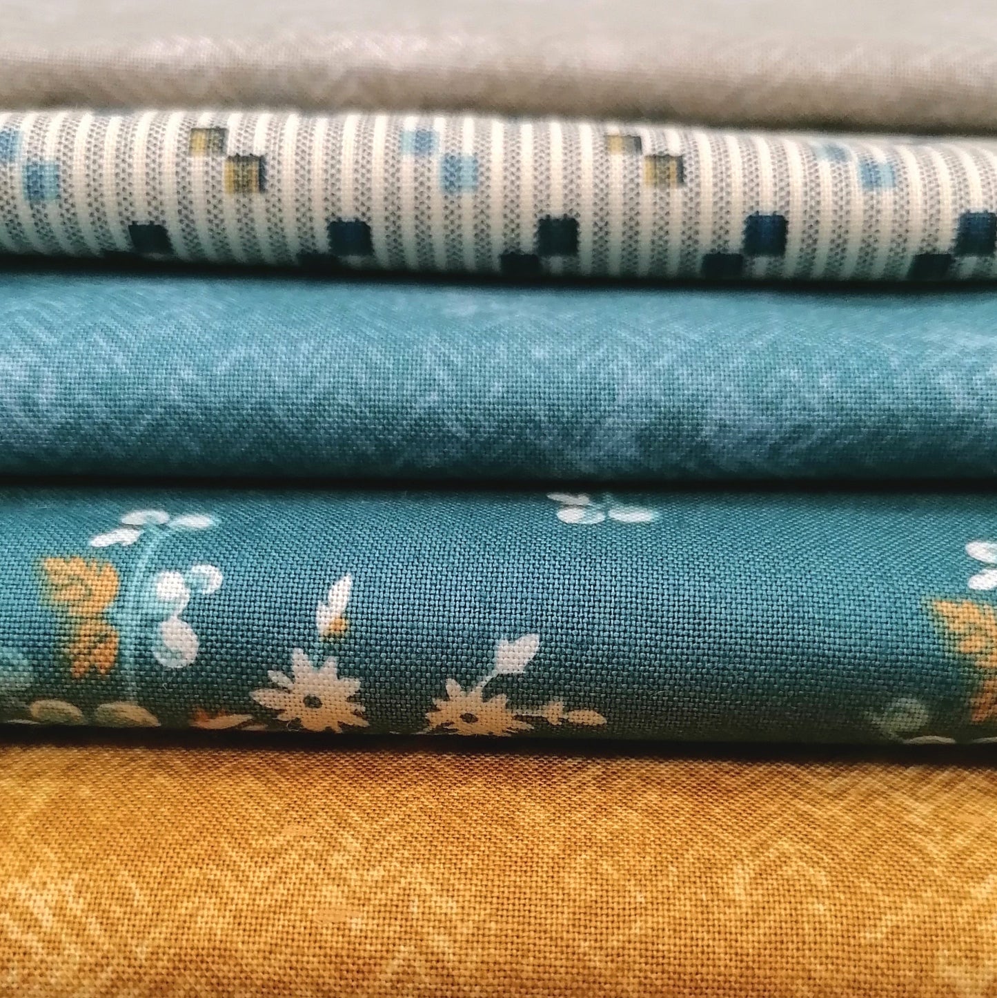 Fat Quarter Bundle LBQ17 - close up detail of teal floral, cream stripe, and mustard gold fat quarters from Laundry Basket Quilts