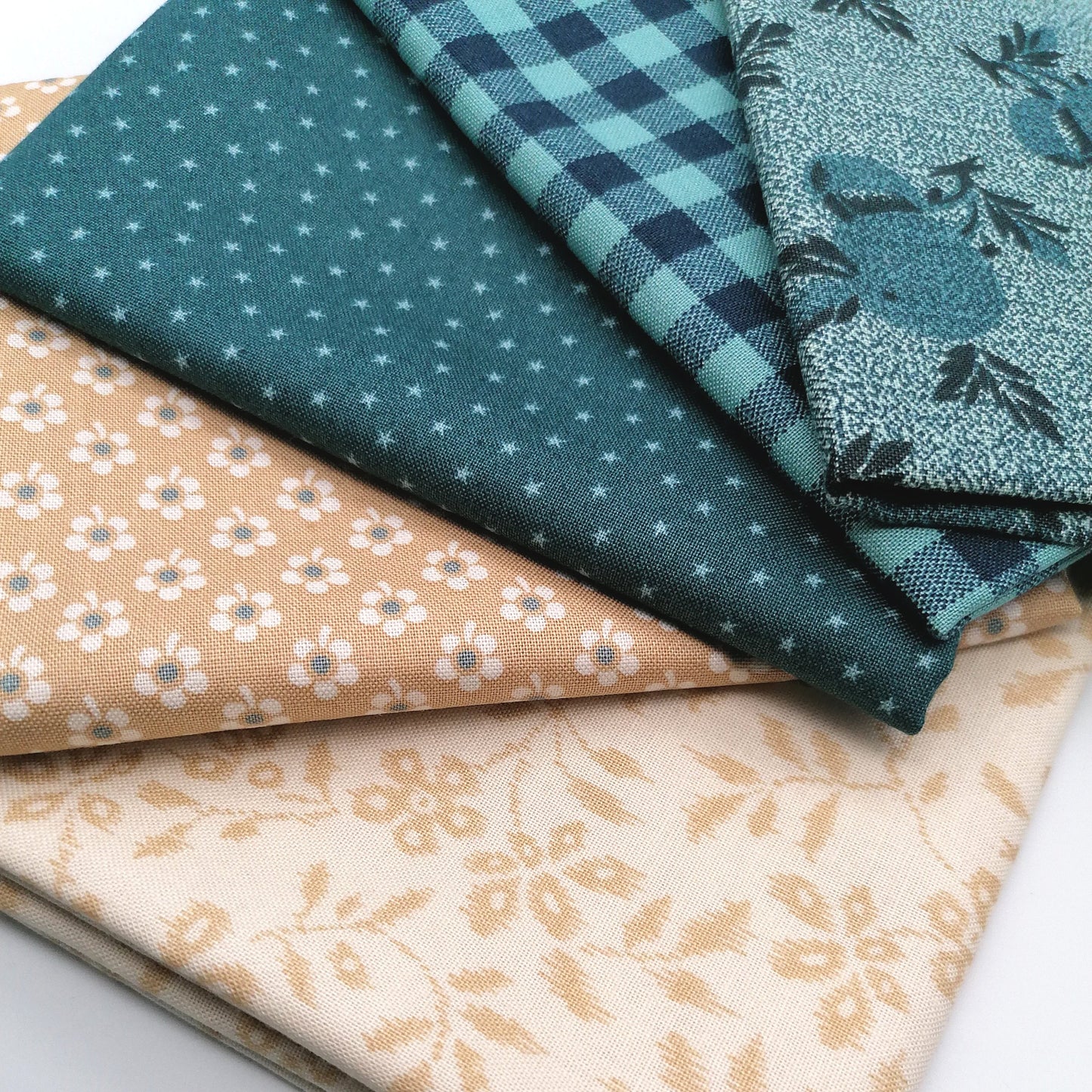 Fat Quarter Bundle LBQ19 - 5 fat quarters fanned showing teal leaf botanical, teal star dot, teal navy gingham, warm sand ditsy floral, and cream gold vine from Laundry Basket Quilts
