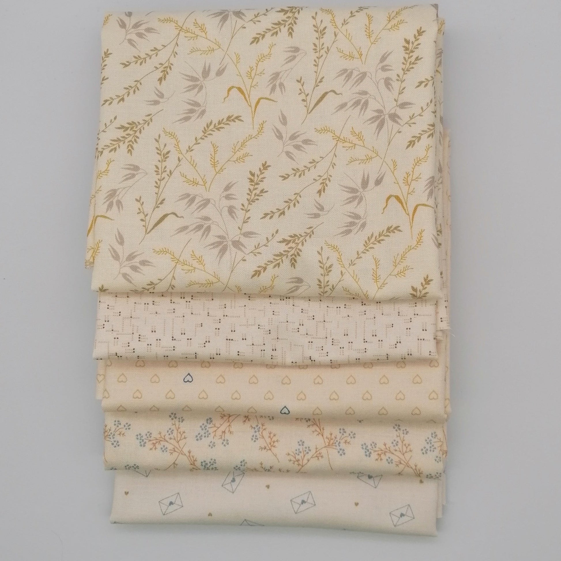 Fat Quarter Bundle LBQ21 - neatly stacked showing all 5 fat quarters including cream botanical, blush hearts, ditsy floral and envelope novelty prints