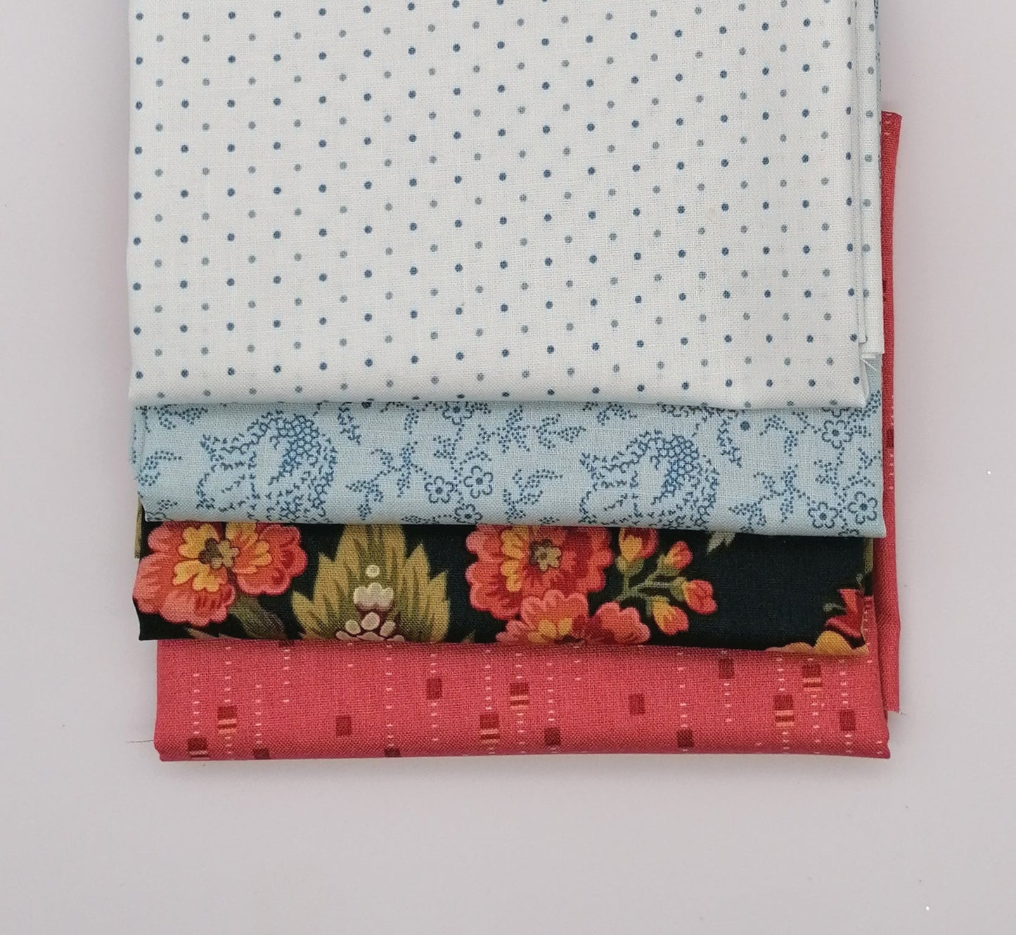 Fat Quarter Bundle LBQ23 - 4 fat quarters fanned showing white grey pin dot, ice blue ditsy floral vine, dark navy coral peony floral, and coral salmon texture from Laundry Basket Quilts