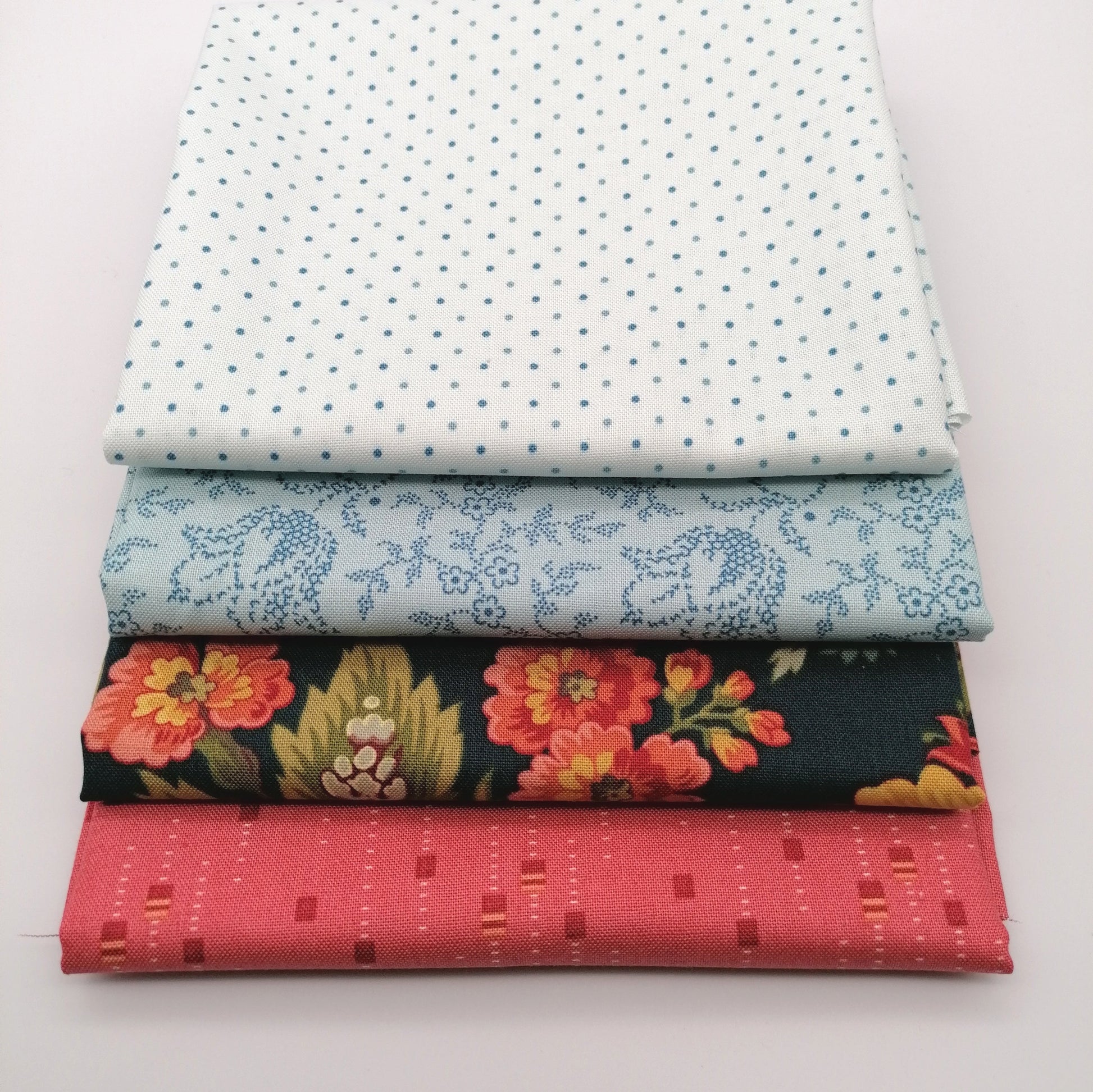 Fat Quarter Bundle LBQ23 - close up stack showing all 4 fat quarters including white pin dot, pale blue ditsy vine, dark navy large peony floral and coral tone-on-tone texture