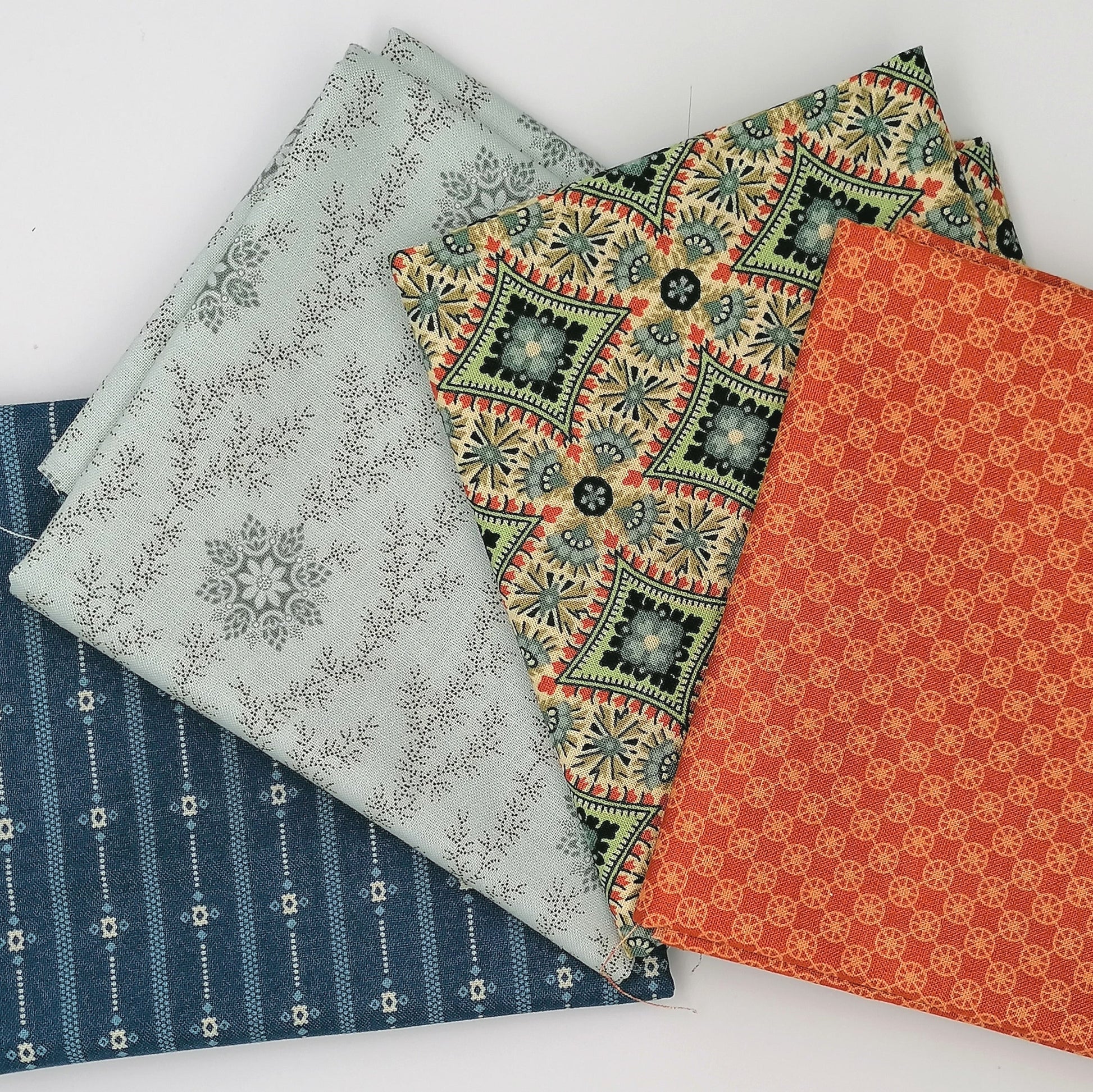 Fat Quarter Bundle LBQ25 - stacked flat lay showing orange circle print, cream tan medallion, pale grey ditsy vine, and navy stripe fat quarters from Laundry Basket Quilts for Andover Fabrics